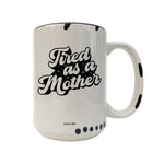 A white ceramic coffee mug with black text reading 'Tired as a Mother' and black polka dot accents, shown on a plain white background.