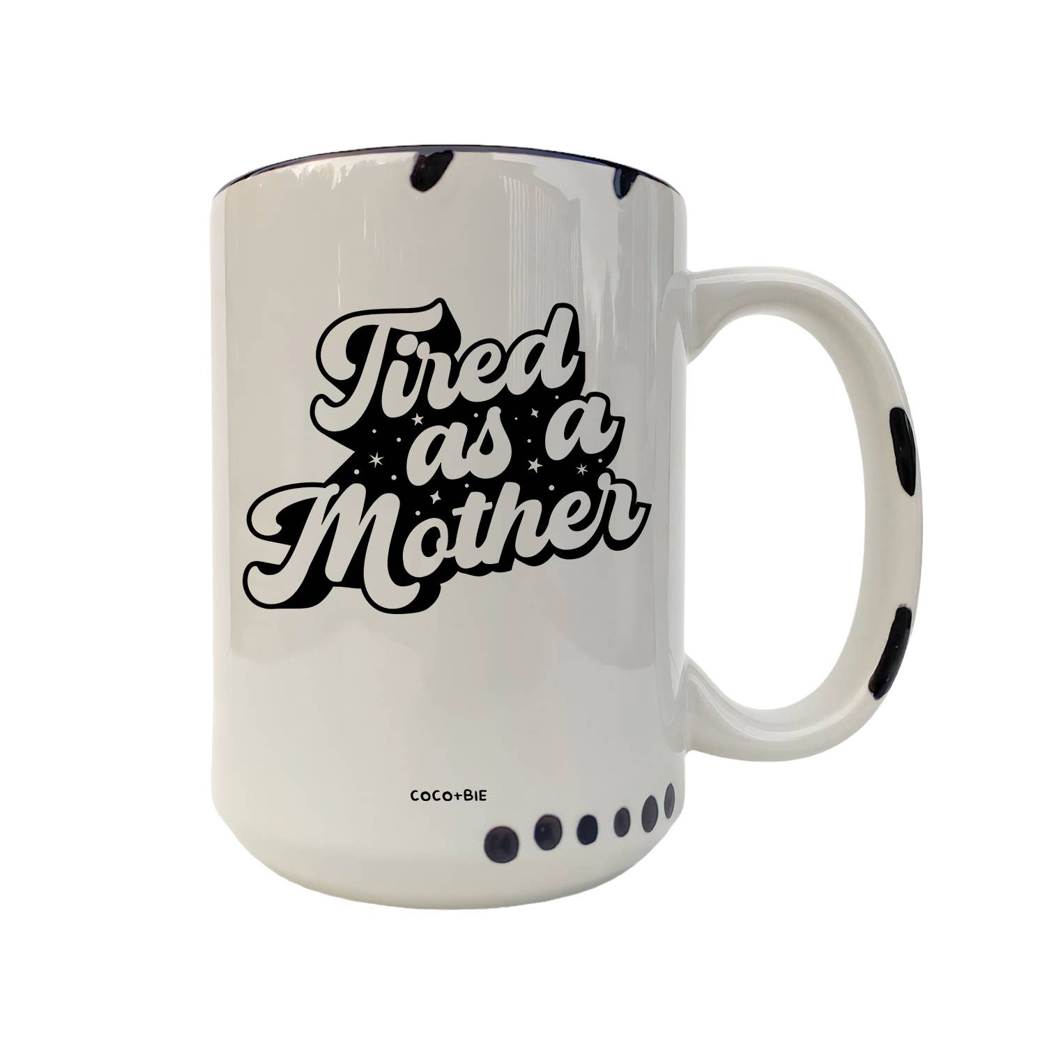 A white ceramic coffee mug with black text reading 'Tired as a Mother' and black polka dot accents, shown on a plain white background.