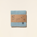 Blue microfiber cloth with cardboard packaging on a beige background